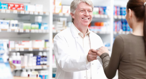 A male pharmacist passing some medication to a woman